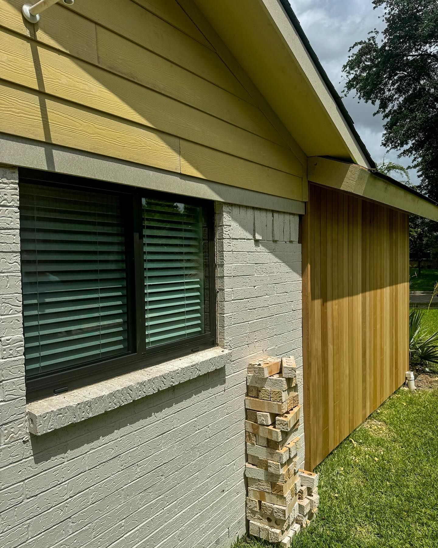 The side of a house with a window and a wooden fence.