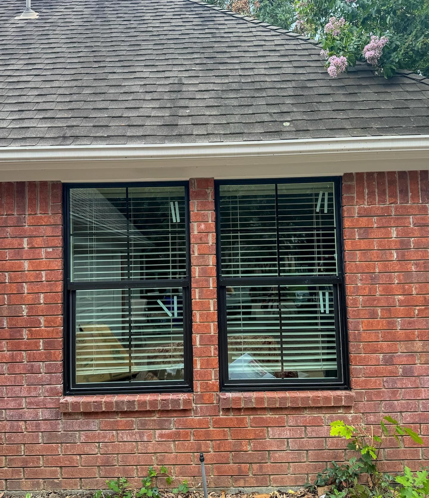 A brick house with two windows and blinds on it