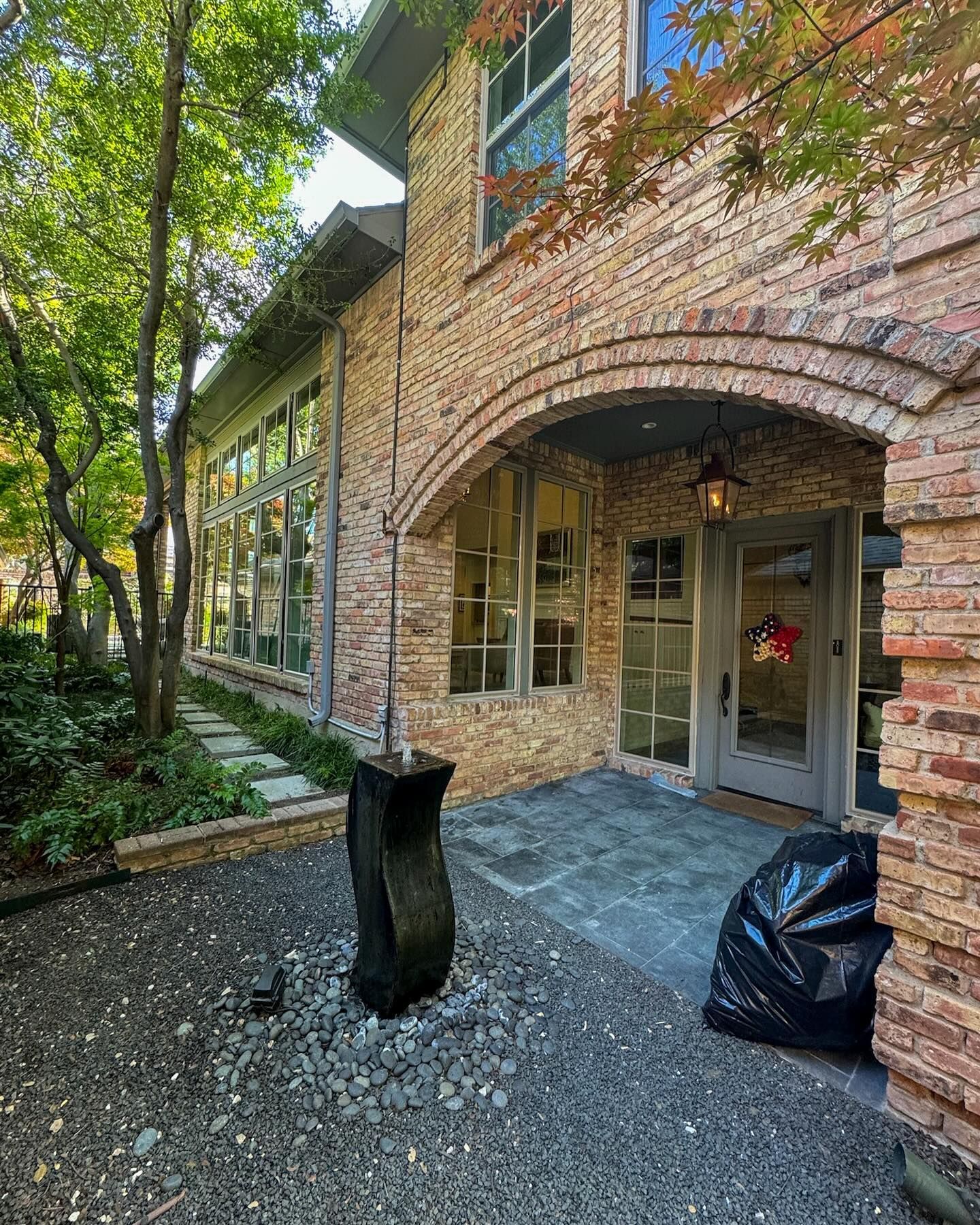 A large brick house with a lot of windows and a black trash bag in front of it.