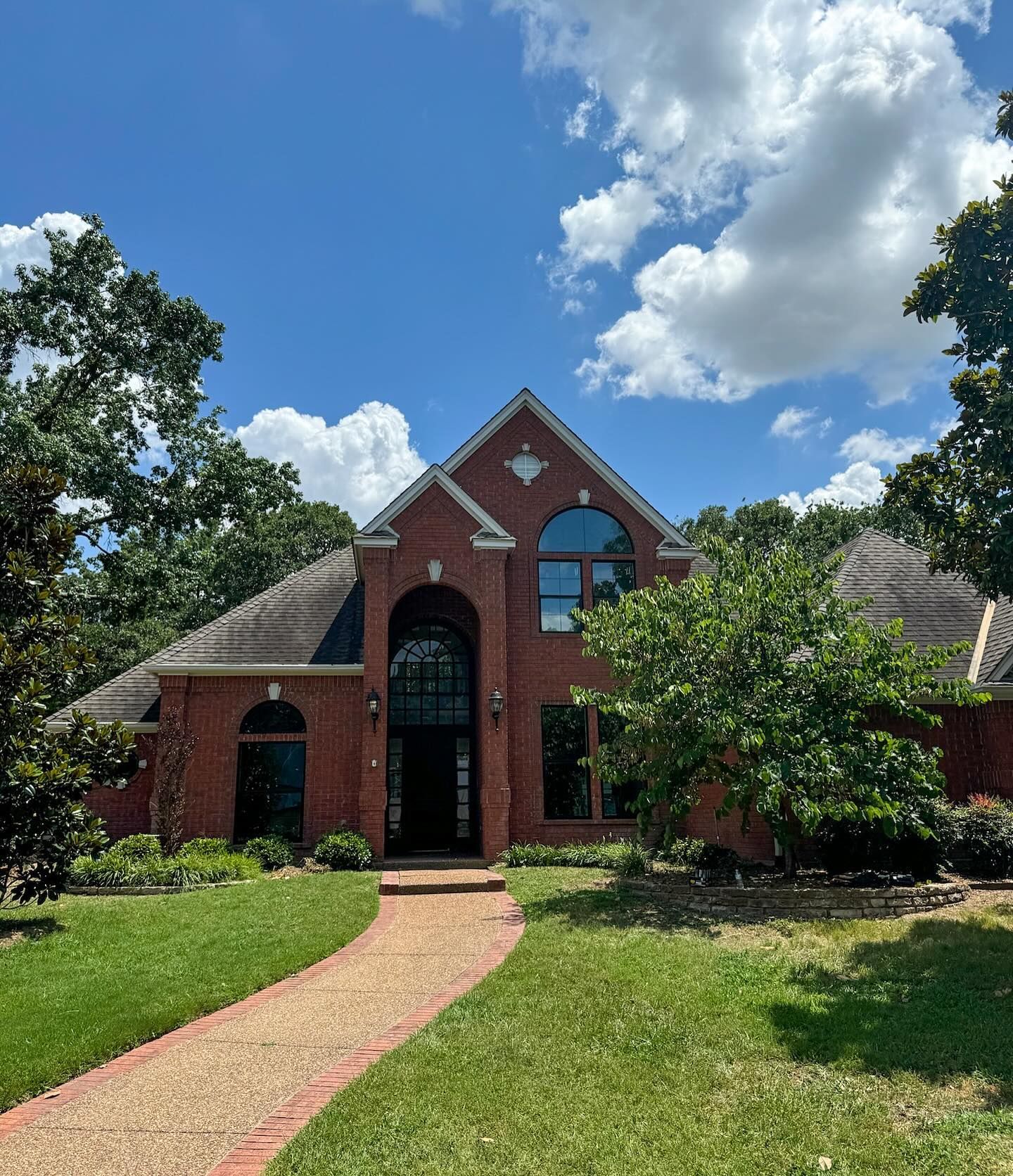 A large brick house with a brick walkway leading to it