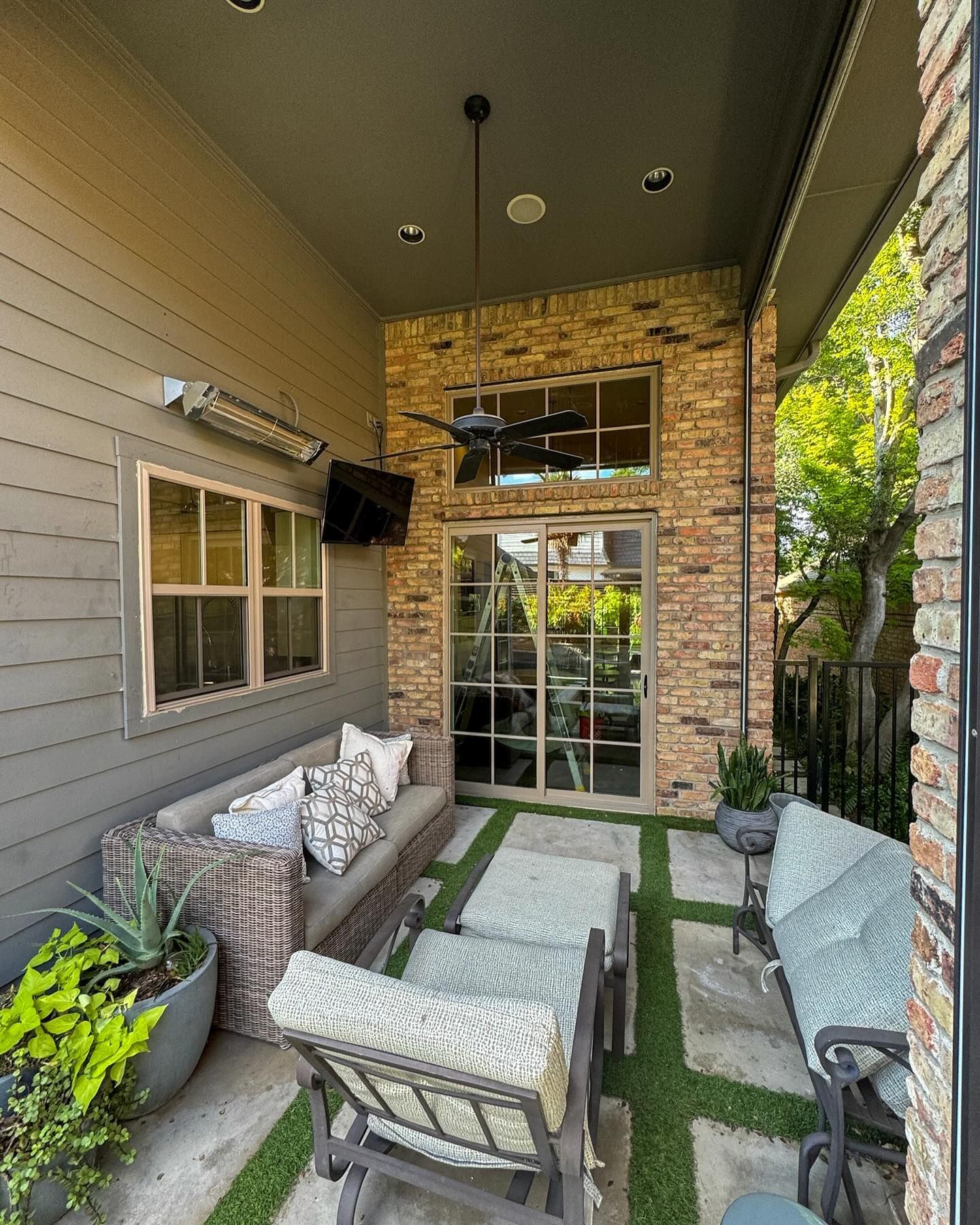 A patio with a couch , chairs , and a ceiling fan.