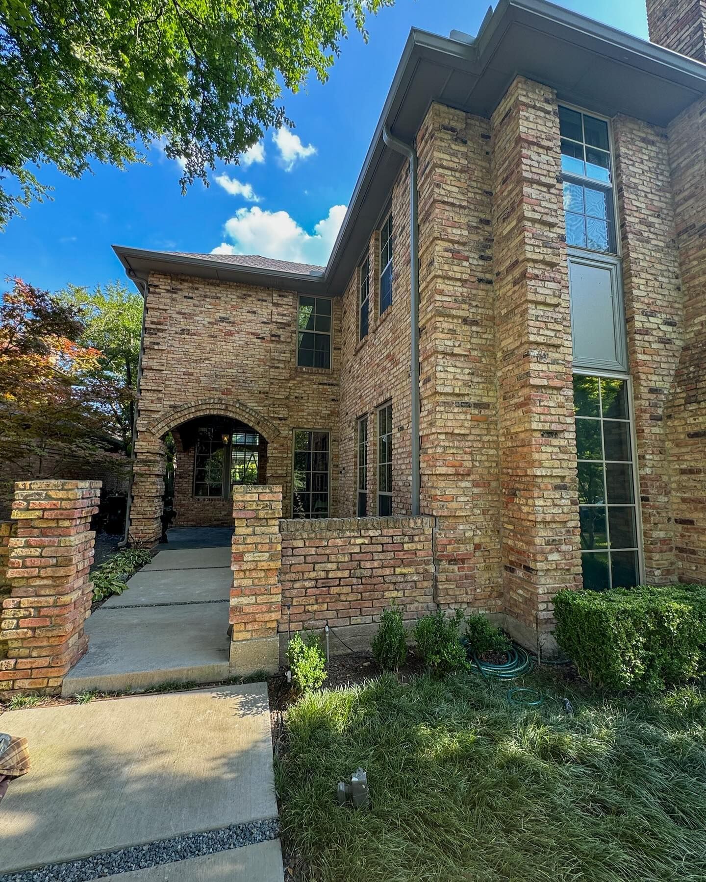 A large brick house with a lot of windows on a sunny day.