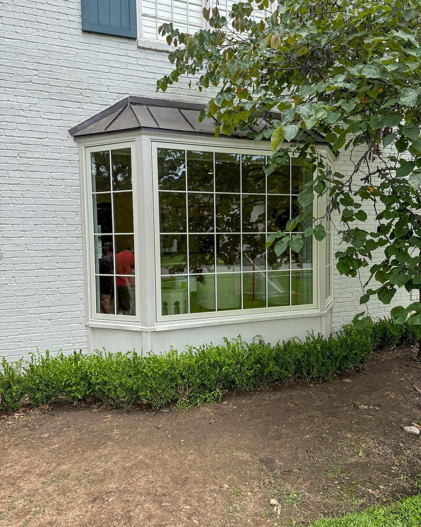 A large window on the side of a white brick house.