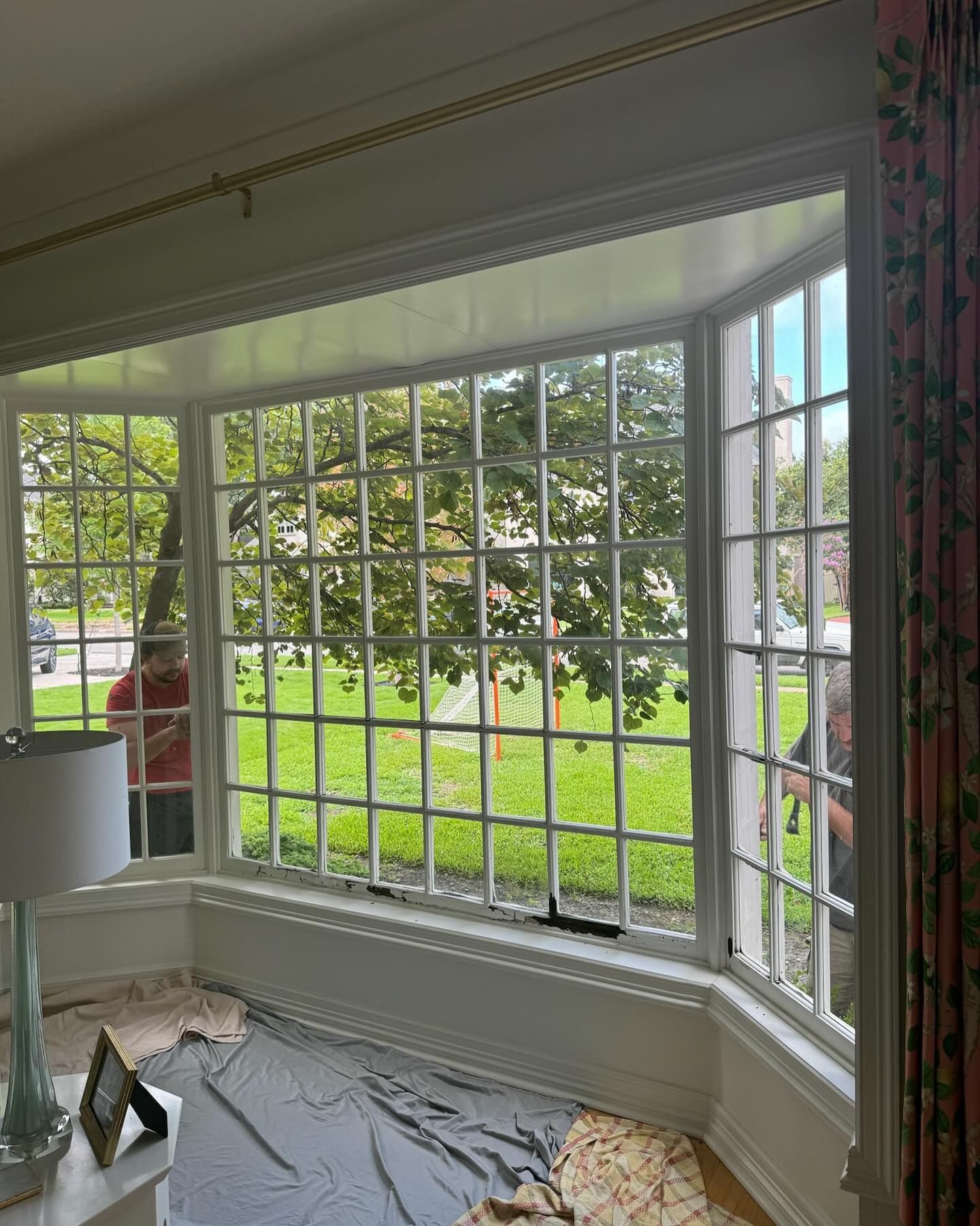A living room with a large bay window and a lamp.