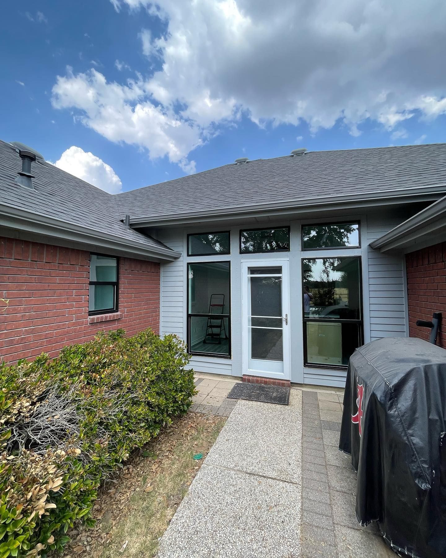 A brick house with a sliding glass door and a grill in front of it.