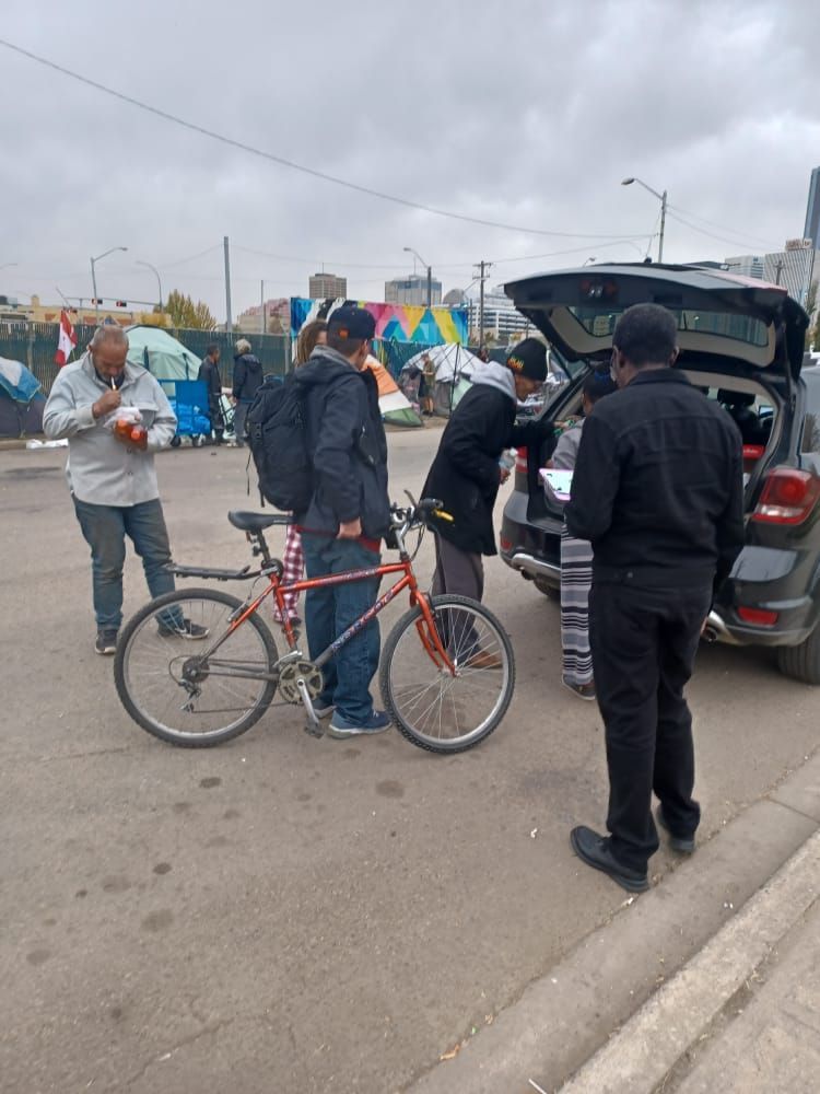 a group of people standing around a bicycle and a car