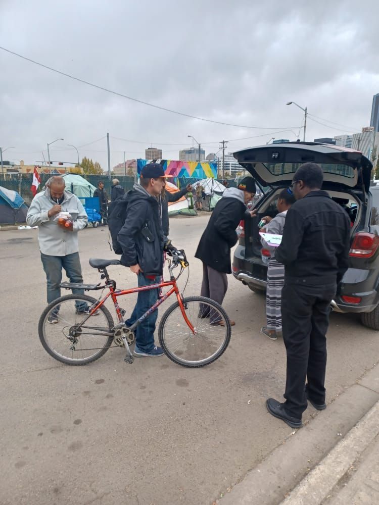 a group of people are standing around a bicycle and a car .