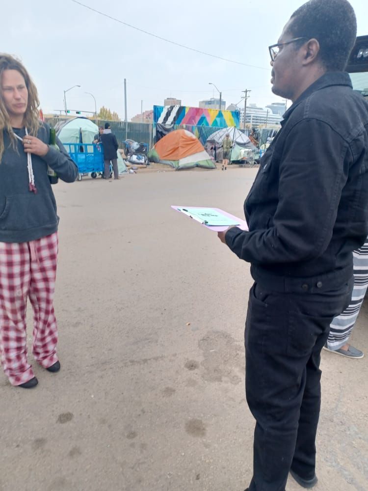 a man and a woman are standing in a parking lot with tents in the background