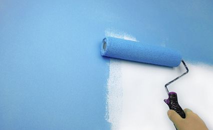 roller painting a wall blue