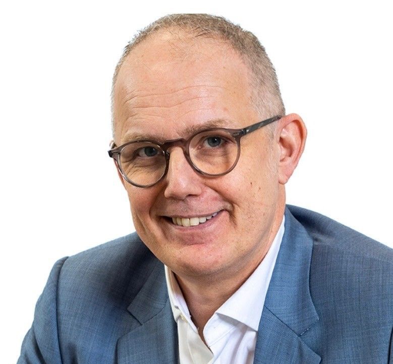 A man in a suit and glasses is smiling for the camera.