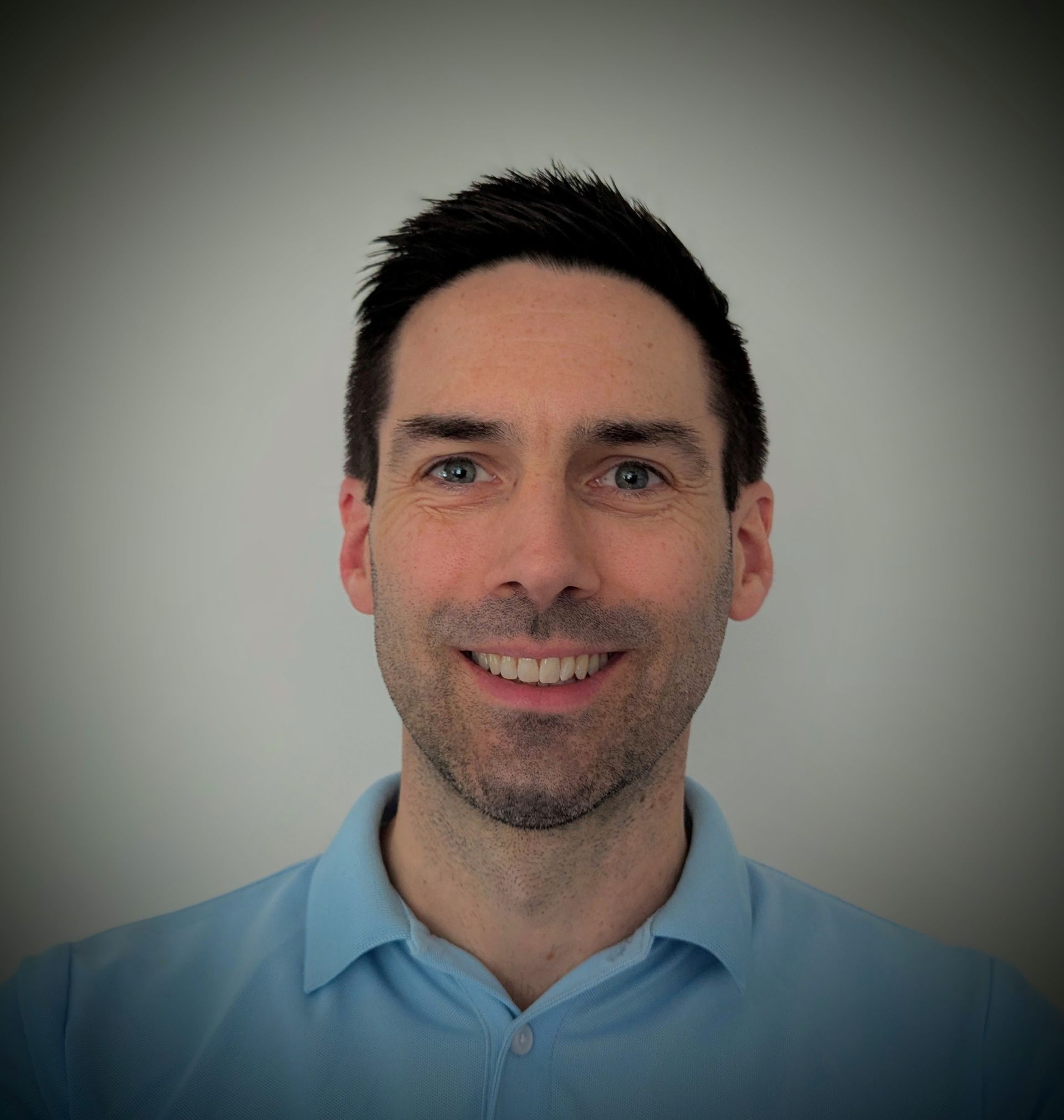 A man in a blue shirt is smiling for the camera.