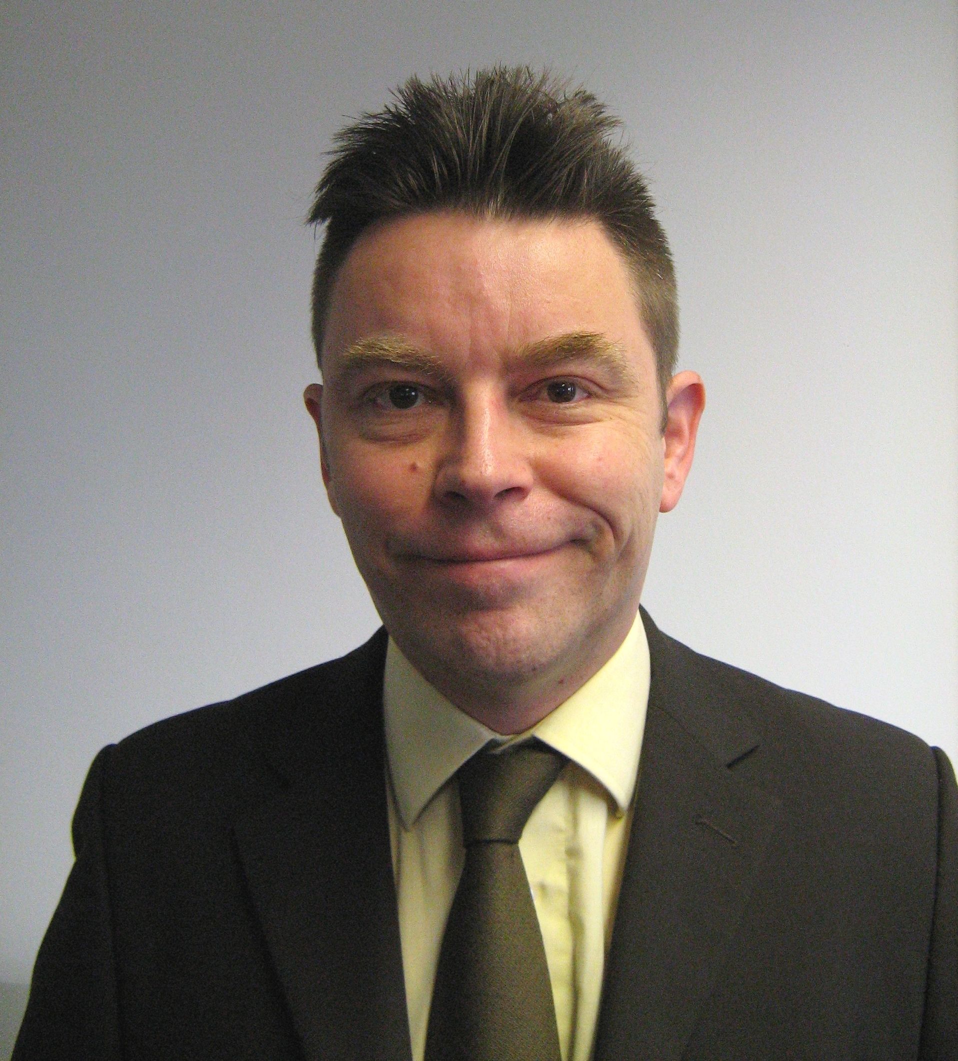 A man in a suit and tie smiles for the camera