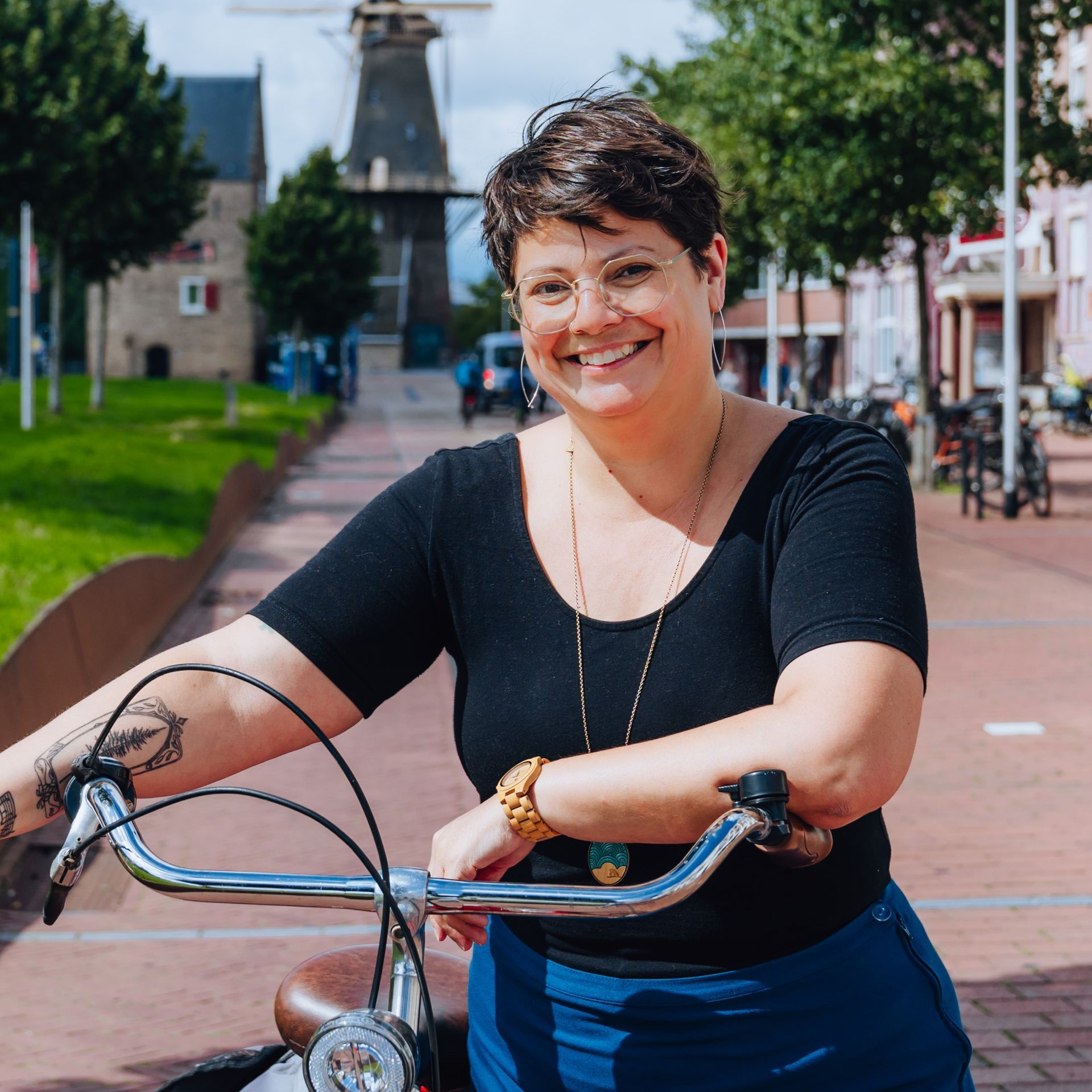 A woman is standing next to a bicycle with a windmill in the background