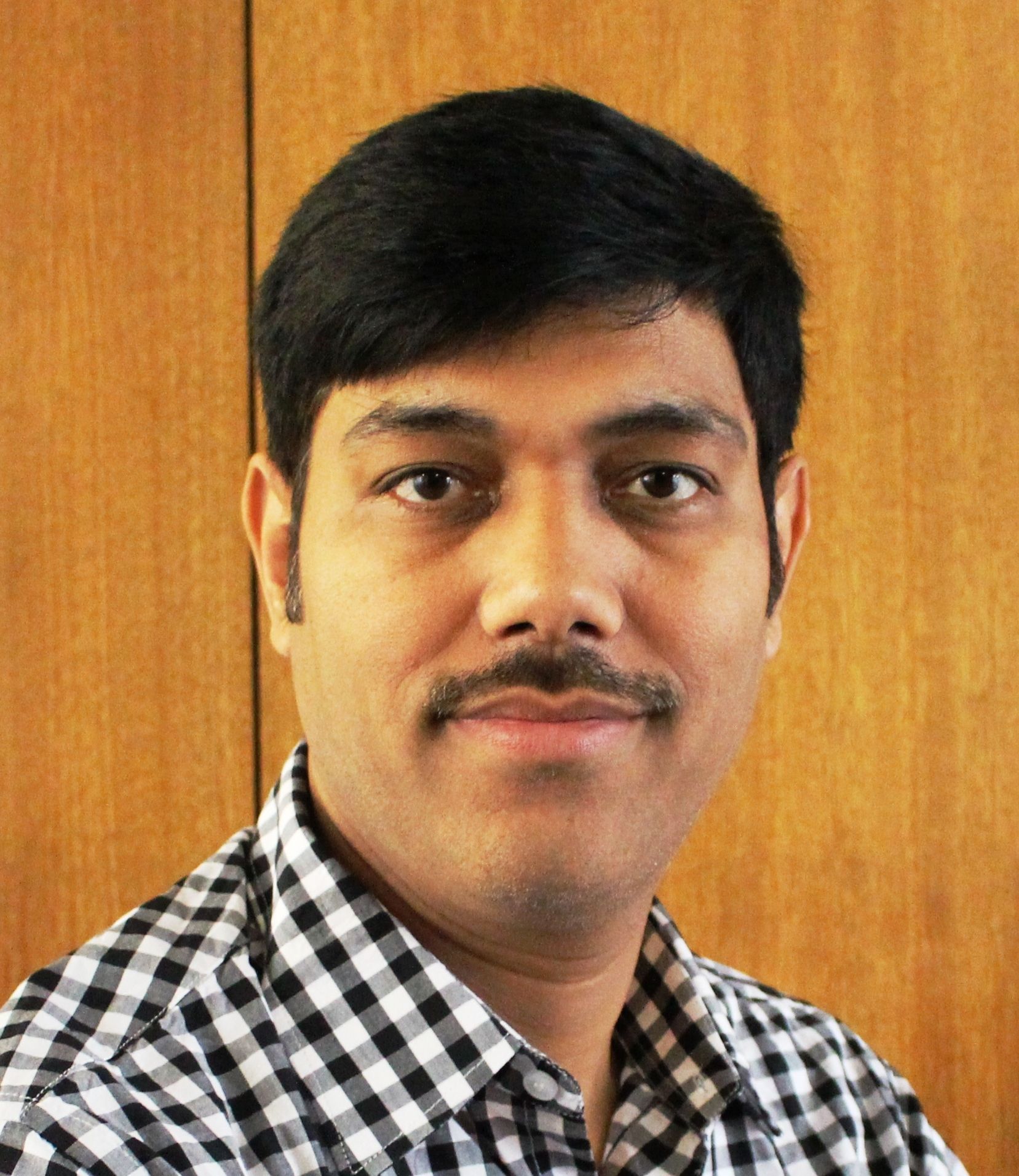A man with a mustache is wearing a black and white checkered shirt.