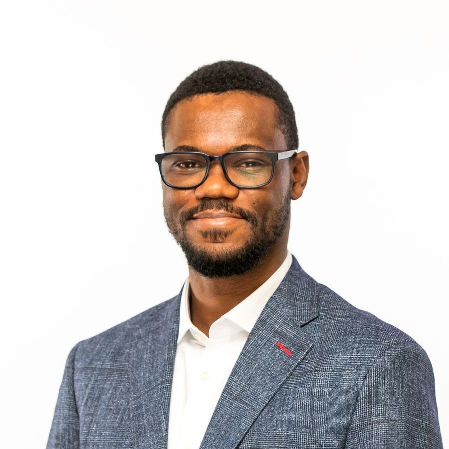 A man wearing glasses and a suit is smiling for the camera.