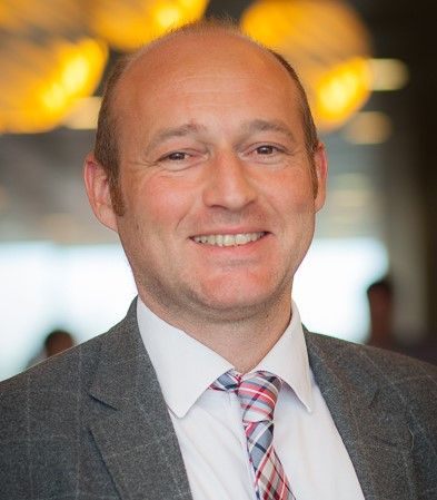 A man in a suit and tie is smiling for the camera