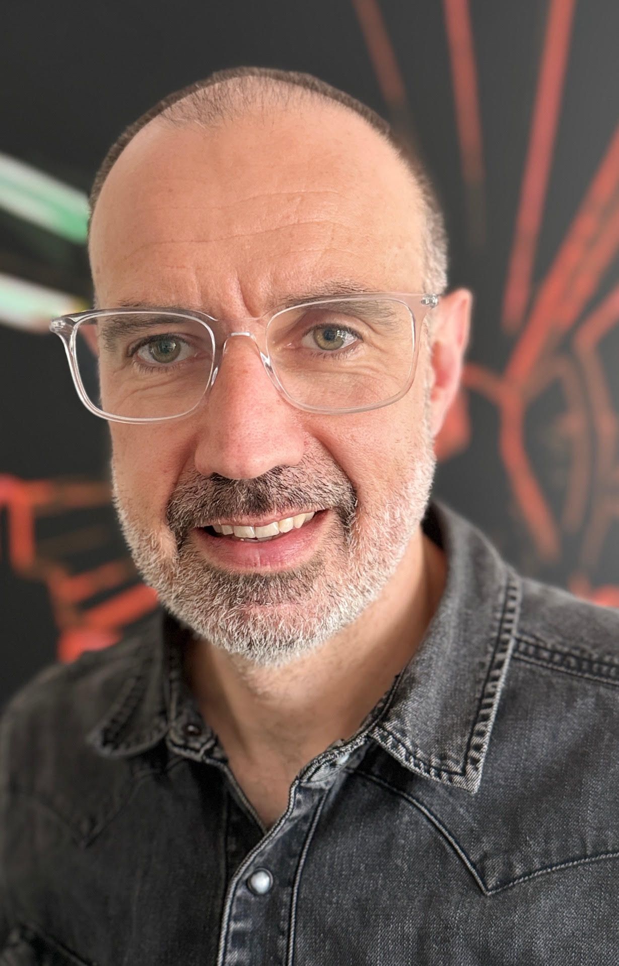 A man with glasses and a beard is smiling for the camera.