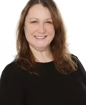 A woman with shoulder-length brown hair wearing a black top, smiling against a plain white background.
