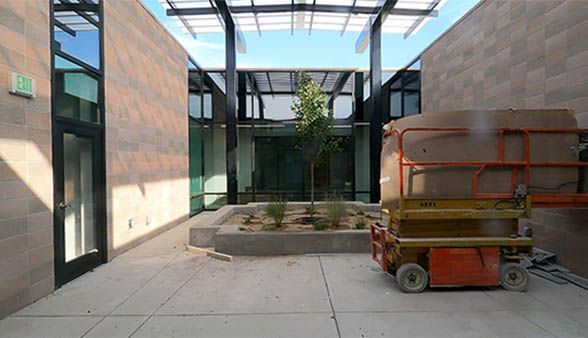 A scissor lift is parked in a courtyard between two buildings.