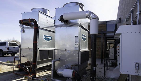 Two cooling towers are sitting outside of a building.