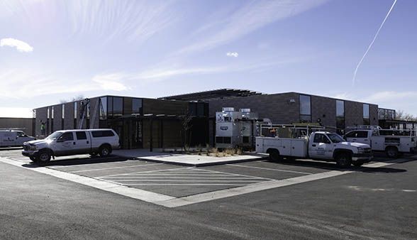 A row of white trucks are parked in front of a building.