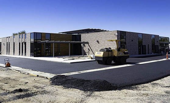 A large building is being built and a bulldozer is parked in front of it.