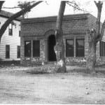 A black and white photo of a brick building with trees in front of it.