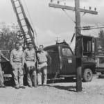 A group of men are standing in front of a truck.