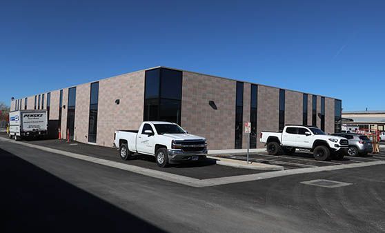 Two white trucks are parked in front of a building.
