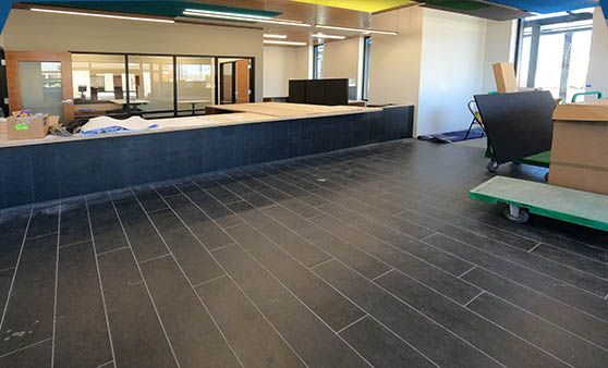 A large empty room with a tiled floor and a green cart.
