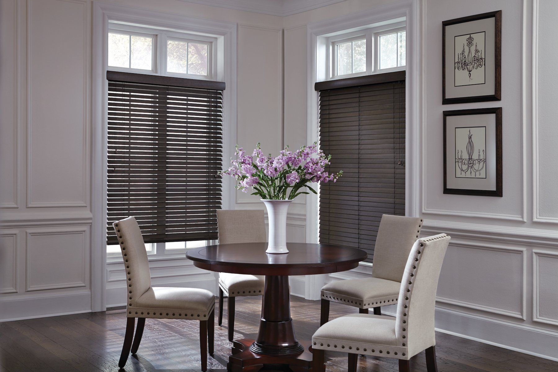 Dining room with dark wood blinds, round table, beige chairs, and floral centerpiece.