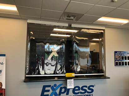 A clear plastic barrier hangs above the service counter at an Express Employment Professionals office.