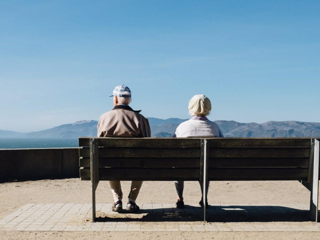 duas pessoas maduras sentadas em um banco olhando para o horizonte
