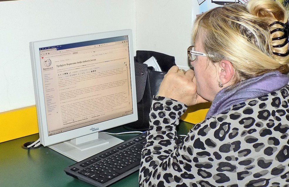mulher madura loira em frente ao computador com a pagina do wikipedia aberta