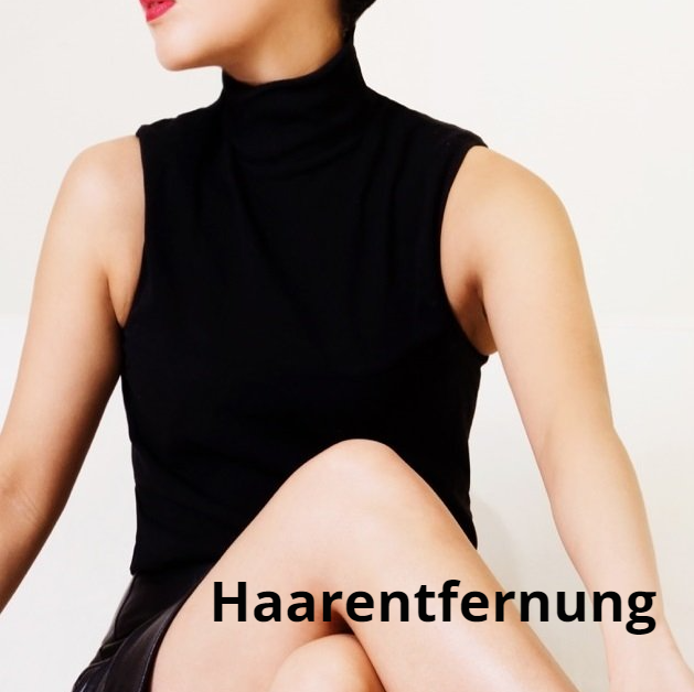 Eine Frau in einem schwarzen Tanktop sitzt mit gekreuzten Beinen