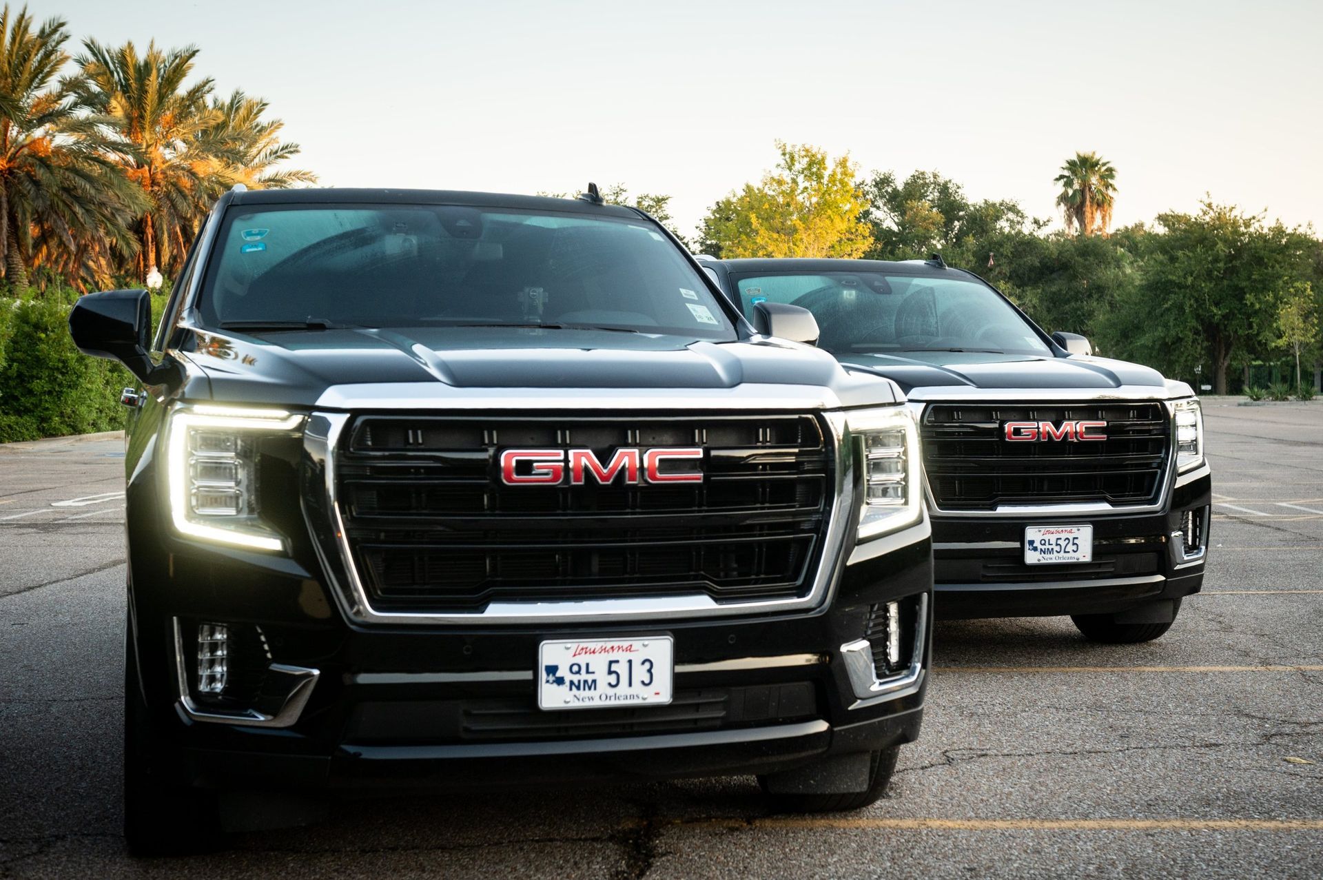 Two black GMC Yukon SUVs parked in a lot.