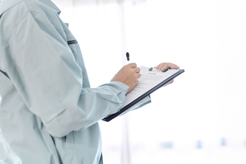 Person in light blue work uniform writing on a clipboard. — Dusted Pest Management in Temora, NSW