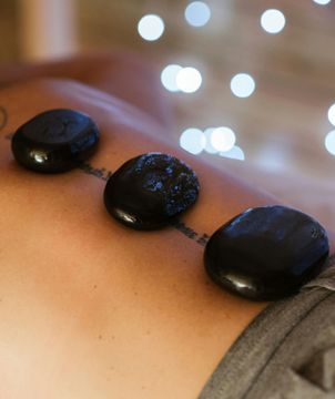 Una mujer está recibiendo un masaje con piedras calientes en la espalda.