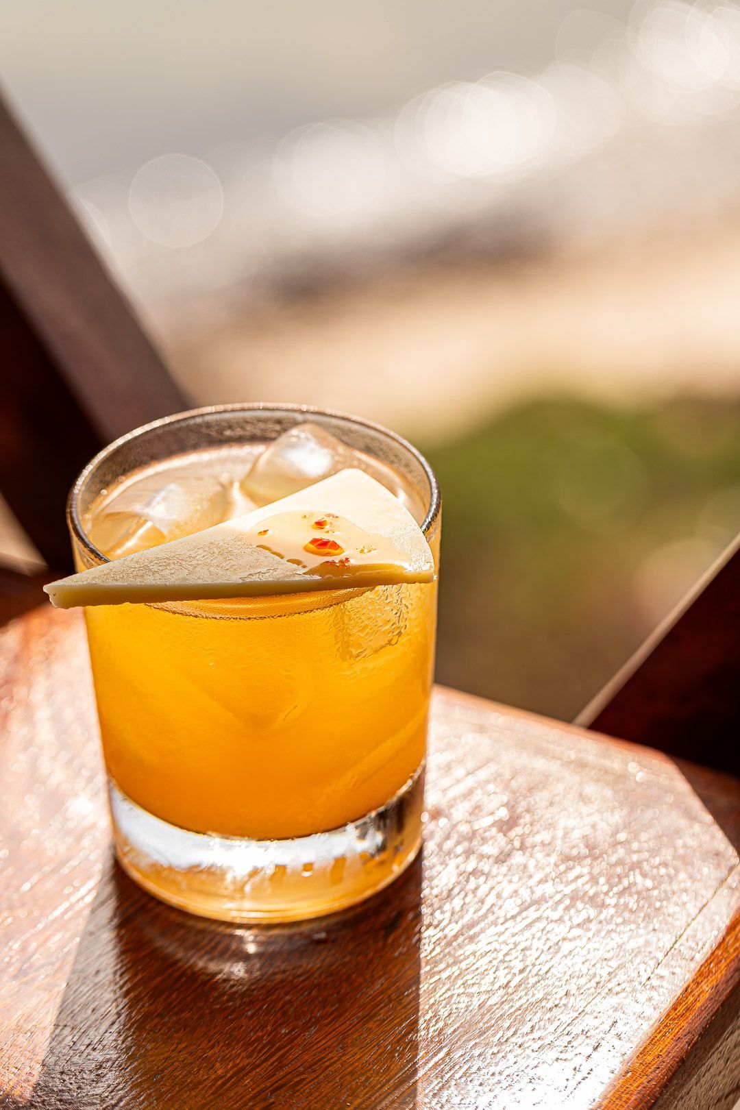 Um prédio de dois andares com telhado inclinado e uma ponte. Um carro vermelho está estacionado em frente. Pessoas caminham sobre a ponte.