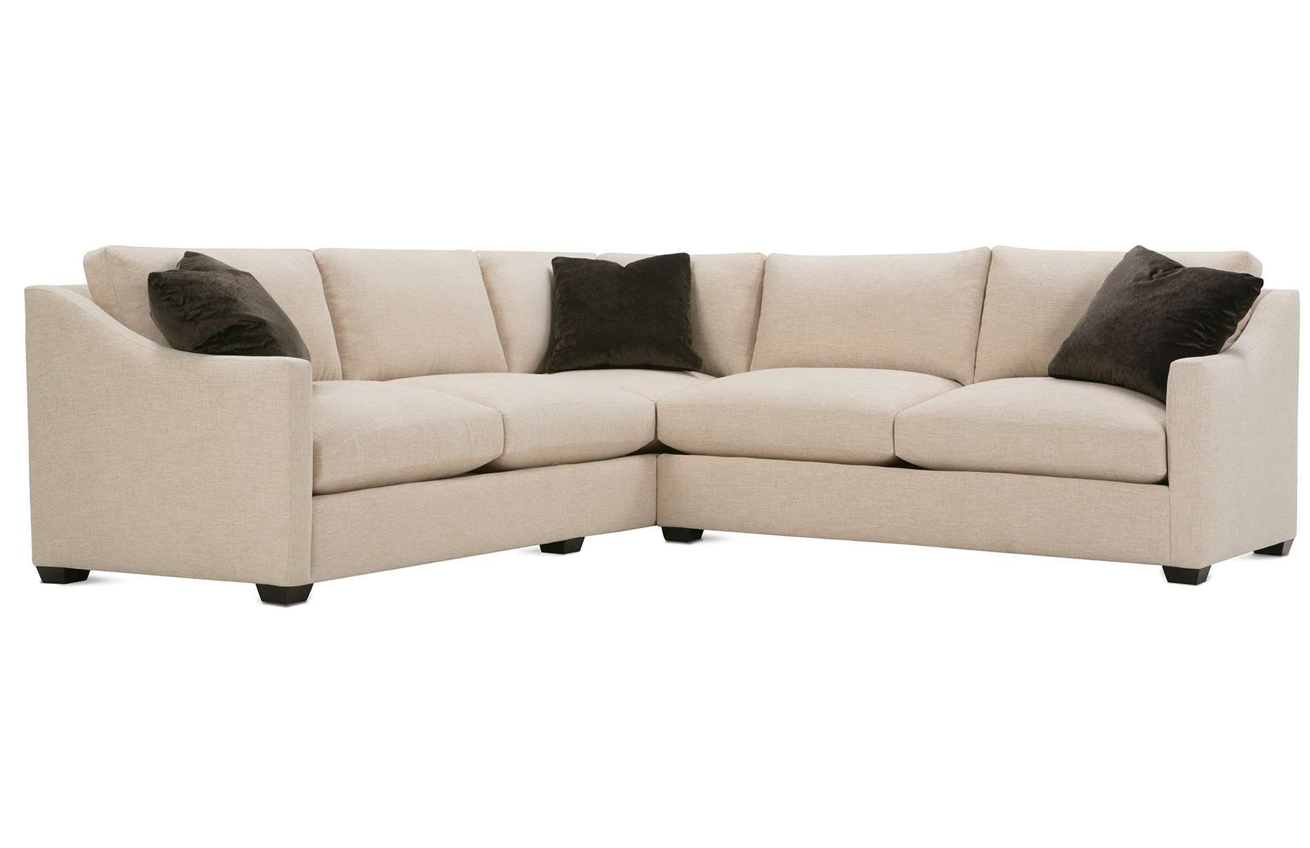 a beige sectional couch with black pillows on it