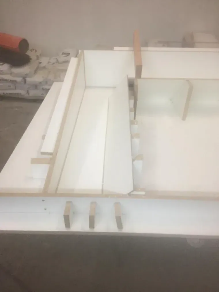 White rectangular forms, possibly molds, with wooden supports on a light-colored surface.