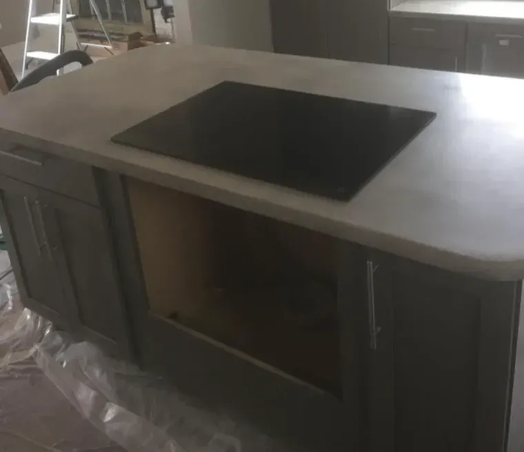 Gray kitchen island with cooktop, unfinished cabinet space.