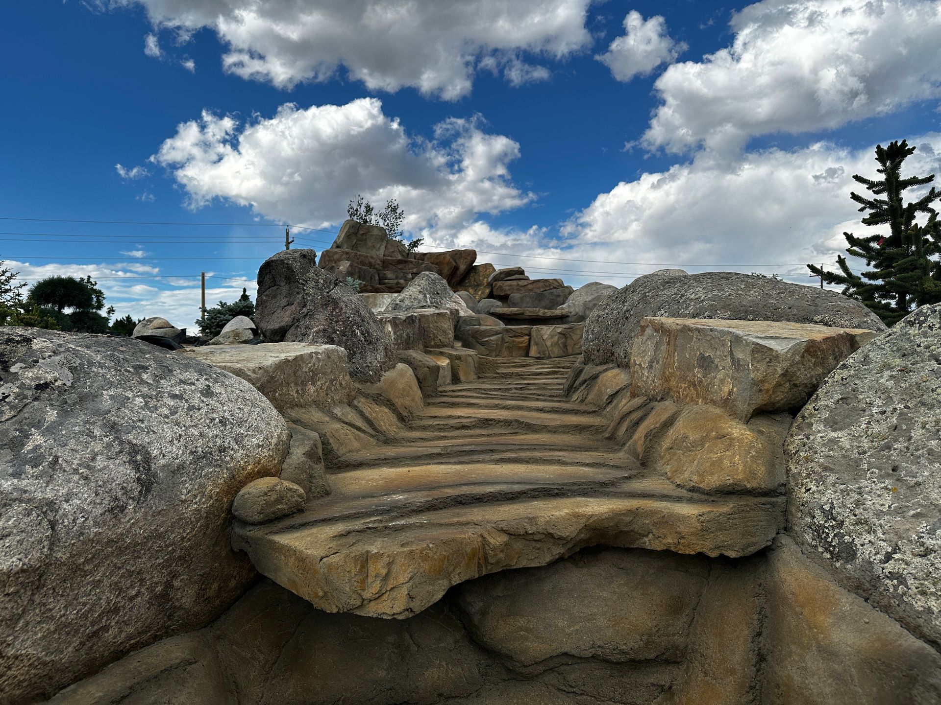 Stone steps leading up a rocky structure under a cloudy blue sky.
