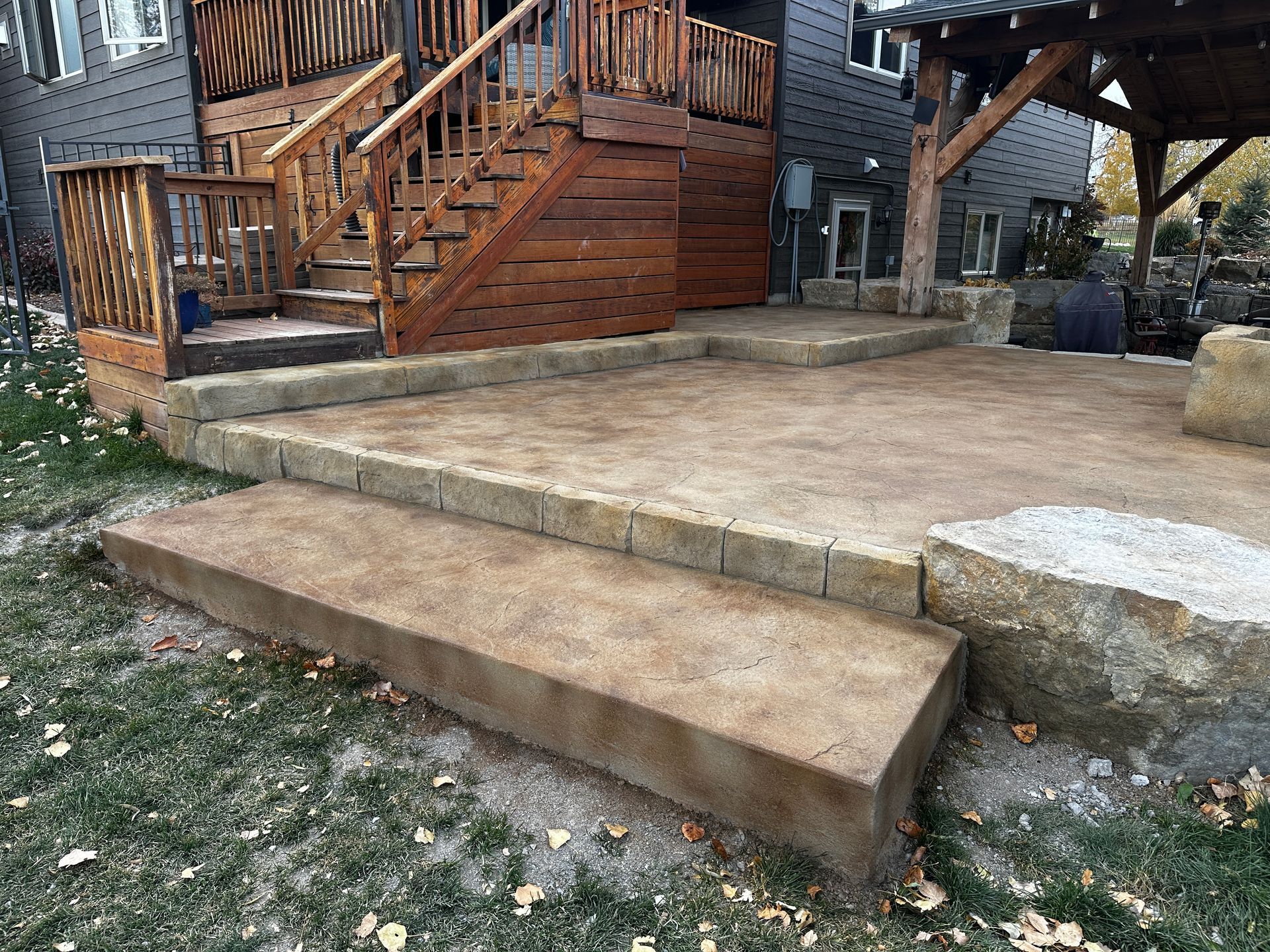 Stone steps and patio with a wooden deck and gazebo in the background.