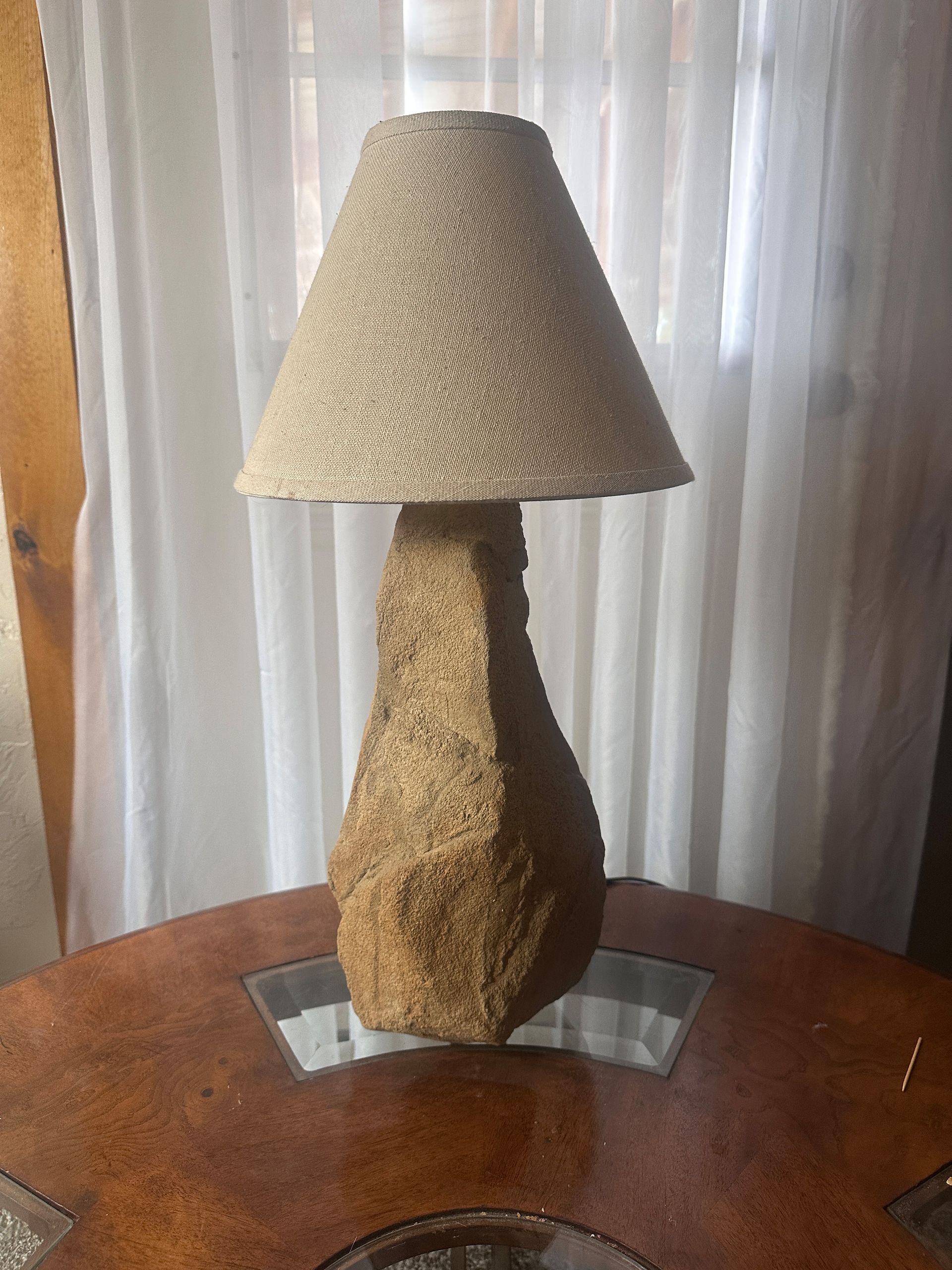 A beige lamp with a textured shade and base sits on a brown table.