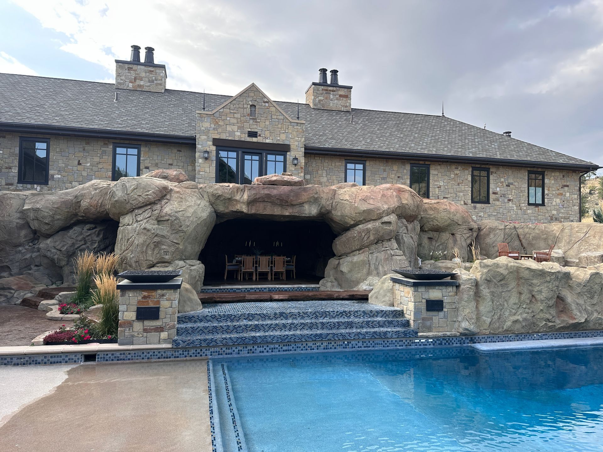 Luxury home with a rock-cave-style outdoor area, waterfall, and pool.