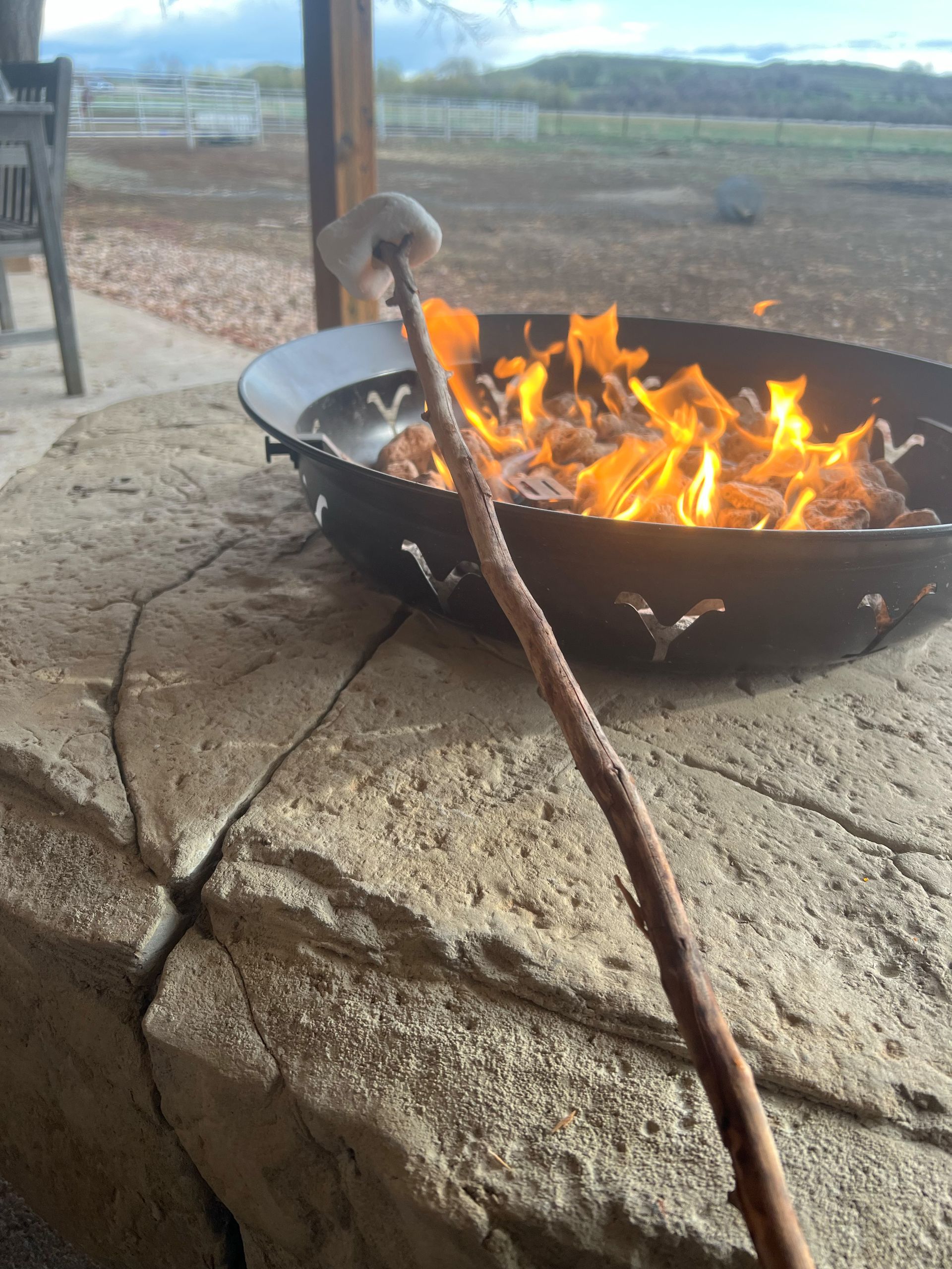 Stone patio with pergola and outdoor kitchen, featuring steps and rock walls.
