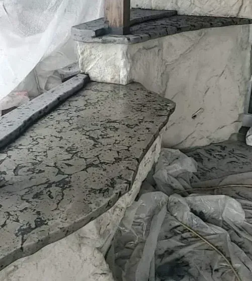 Concrete stairs and wall with a textured finish, covered in plastic sheeting.