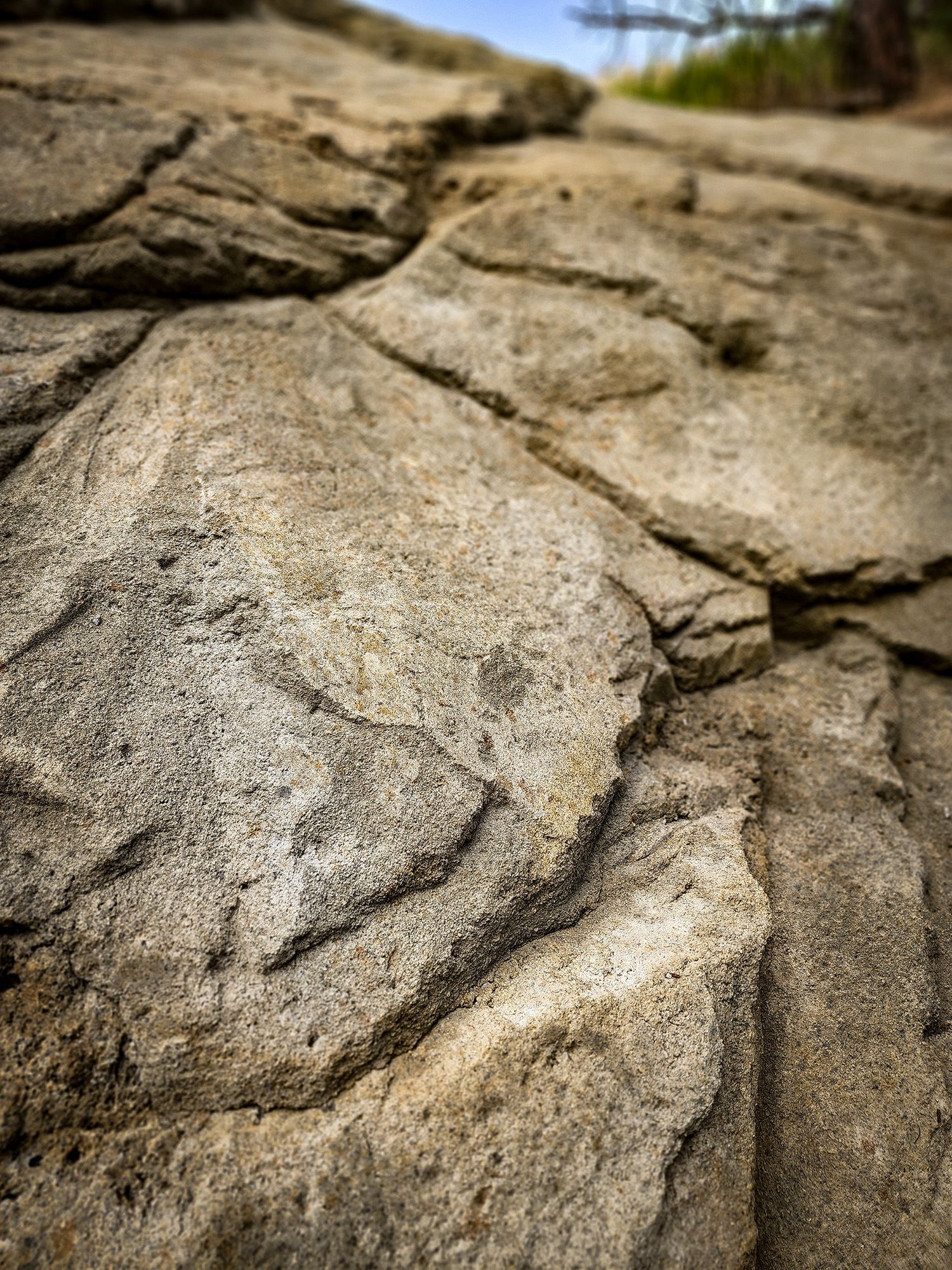 Textured light brown rock formation with cracks, viewed from a close-up angle.