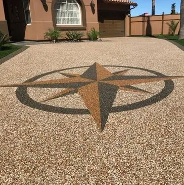 Driveway with compass rose design, beige and black gravel.